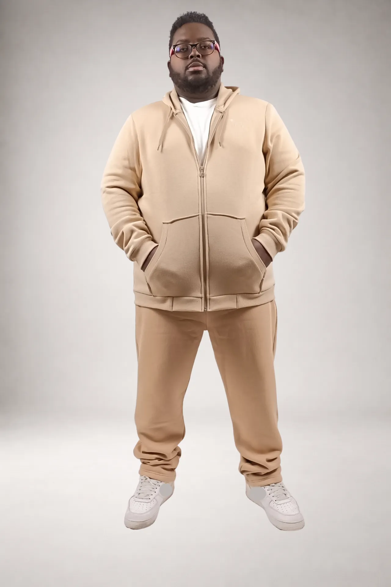 Ensemble sweat à capuche manches longues zippé et pantalon de jogging colori sable 56% coton 44% polyester porté sur un t-shirt blanc. Fabrication européenne - Porté en 3XL - Vue de face - Cordelette de serrage, 2 poches kangourou, brodé du chien de la marque l'homme MBR. 2 Poches latérales au pantalon. Coupe droite pour le bas de pantalon. Hoodie unisexe.